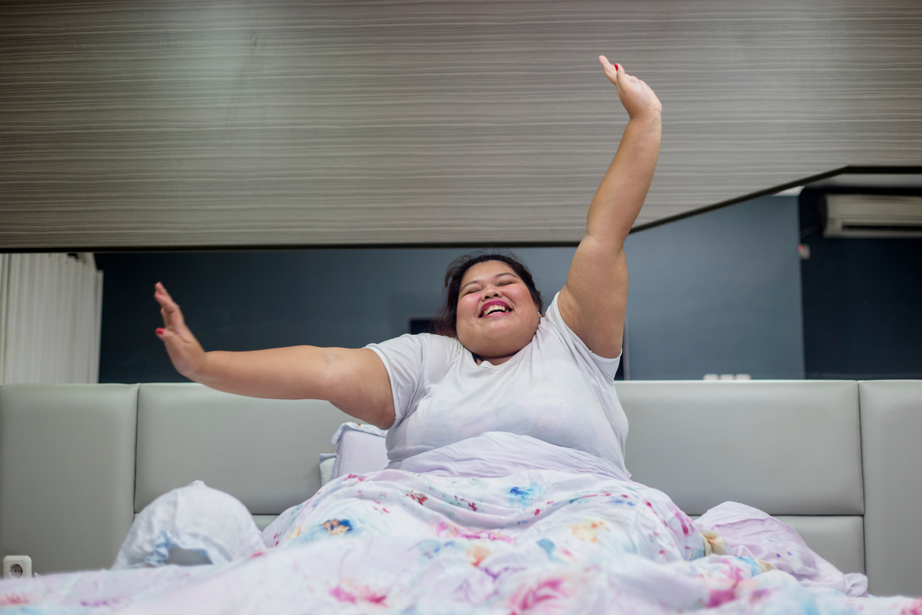 Plus Size Woman Stretching Arms in Bed 